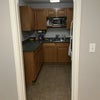 Photo 5: Small kitchen with fridge, sink, microwave and oven.